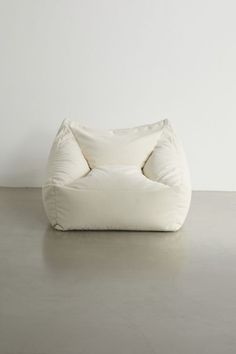 a white bean bag chair sitting on top of a cement floor next to a wall