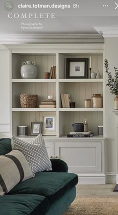 a green couch sitting in front of a white book shelf filled with books and vases