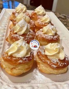 several pastries on a white plate with powdered sugar and icing around them