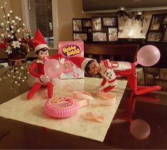 two elfs are on the table with some candy and balloons in front of them