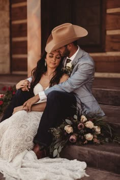 a bride and groom are sitting on the steps in front of an old building wearing cowboy hats