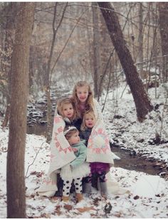 three children are sitting on the ground in the snow with their mother and two other children