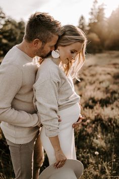 a man and woman are standing in the grass with their heads close to each other