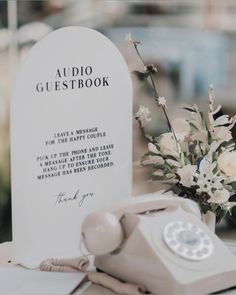 an old phone sitting on top of a table next to a white tombstone with flowers in it