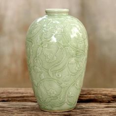 a green vase sitting on top of a wooden table