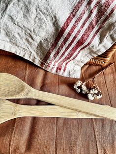 two wooden spoons sitting on top of a table next to a basket and towel