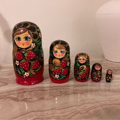 a group of russian nesting dolls sitting on top of a counter next to a vase