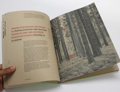 a hand holding an open book with trees in the background