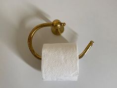 a gold toilet paper holder on a white wall