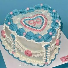 a decorated cake with blue icing and pink decorations on it's sides, sitting on a table