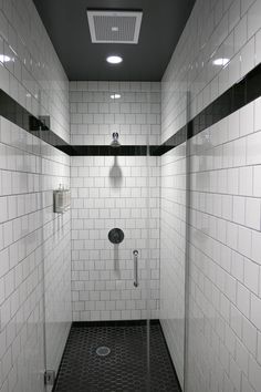 a bathroom with black and white tiles on the walls, shower head and hand rail