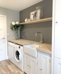 a washer and dryer in a small room with open shelving on the wall