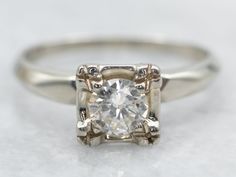 an engagement ring with a square cut diamond in the center, on a white surface