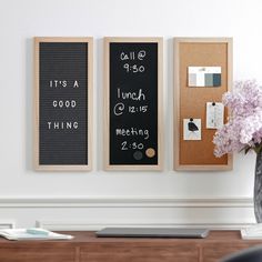 a vase with flowers sitting on top of a desk next to two framed chalkboards