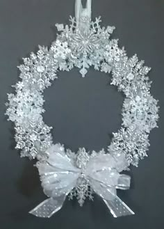 a white christmas wreath with bows and snowflakes hanging from the side on a black background