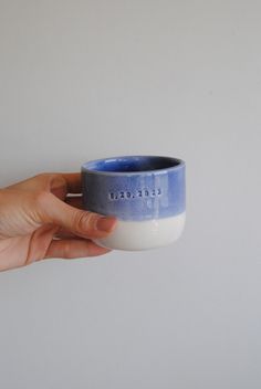 a hand holding a blue and white cup