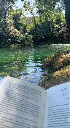 an open book sitting next to a river