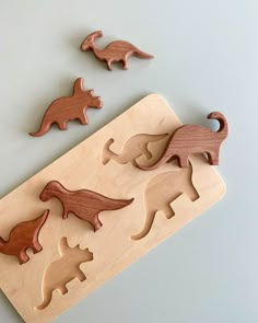 three wooden dinosaurs on a cutting board