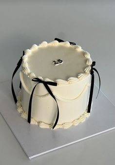 a white cake sitting on top of a silver plate with black ribbon around the edge