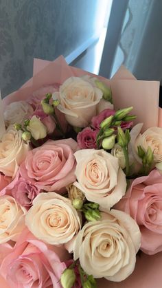 a bouquet of pink and white roses sitting on top of a table