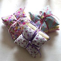 four pillows tied together with ribbons on a white tablecloth covered surface, all in different patterns and colors