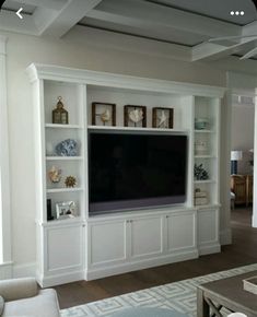 a living room with white built in shelves and a flat screen tv mounted on the wall