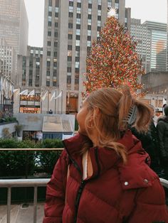 a woman standing in front of a christmas tree