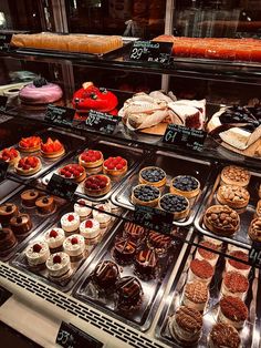 a display case filled with lots of different types of cakes and pastries on top of it