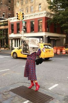 a woman standing on the side of a street holding up a newspaper in front of her face