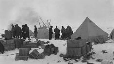 an old black and white photo of people standing in the snow next to some tents