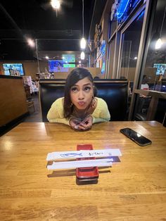 a woman sitting at a table with two cell phones on top of it and an object in front of her