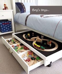 a child's bedroom with toy train tracks and toys in the drawer under the bed