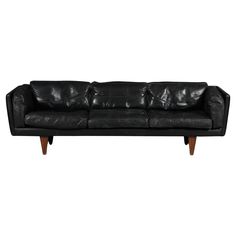 a black leather couch with wooden legs