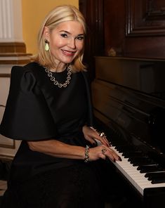 a woman sitting at a piano smiling for the camera