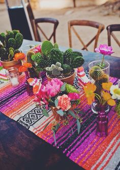 a table topped with potted plants on top of a wooden table covered in colorful cloth