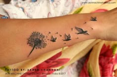 a woman's arm with a dandelion tattoo on it