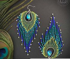 two peacock feathers with beaded earrings next to each other