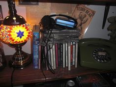 a lamp sitting on top of a wooden table next to a pile of books and cds