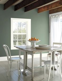 a dining room table with chairs and a bowl of fruit on top of the table