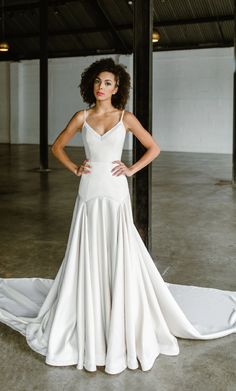 a woman in a white wedding dress posing for a photo with her hands on her hips