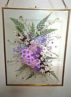 a glass frame with flowers hanging on the wall