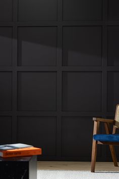 a chair and table in front of a wall with black paneled panels on it