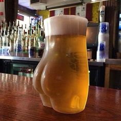 a glass of beer sitting on top of a wooden table in front of a bar