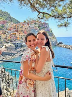 two girls hugging each other in front of the ocean