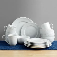 a stack of white dishes sitting on top of a blue place mat