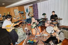 a group of young people playing guitars in a room full of musical instruments and music equipment