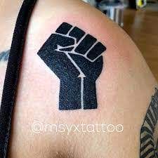 a man with a tattoo on his arm holding up a fist