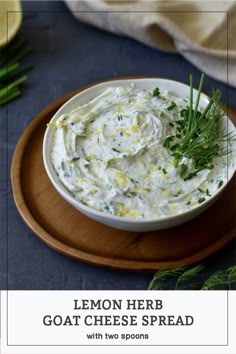 lemon herb goat cheese spread with two spoons on a wooden platter next to fresh herbs