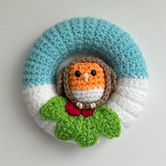 a crocheted brooch with an owl on it's head and green leaves