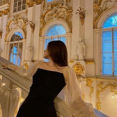 a woman in a black dress is standing on the stairs